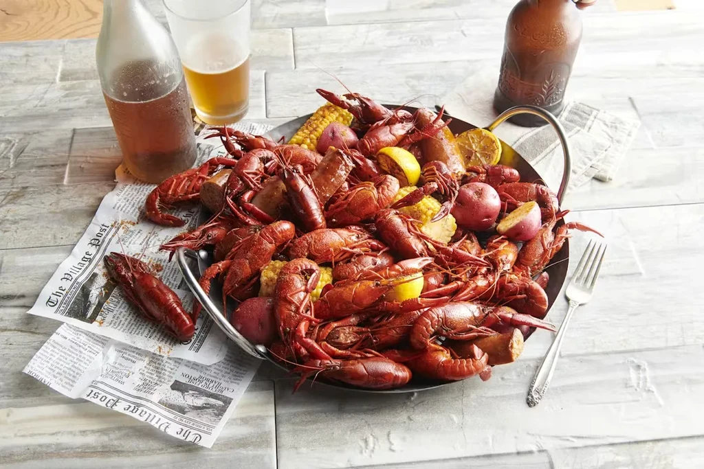 Overhead: Crawfish boil with corn, potatoes, sausage, lemons on newspaper.