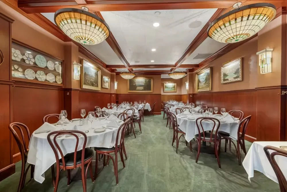 Empty, elegant restaurant dining room with stained glass and set tables.