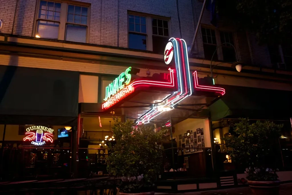 Jake's Famous Crawfish exterior at night, with prominent neon signage.