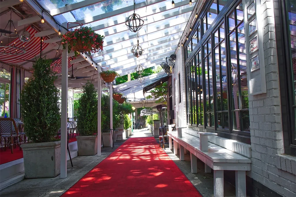 Restaurant patio with red carpet, transparent roof, plants, and dining area.