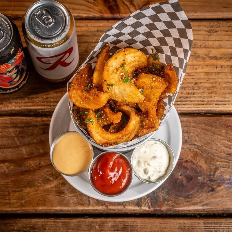 Fries in a cup, three sauces, and a Rainier beer can.