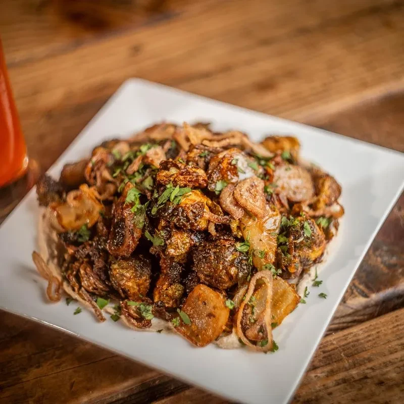 Caramelized brussels sprouts, crispy onions, and fresh herbs on a white plate.