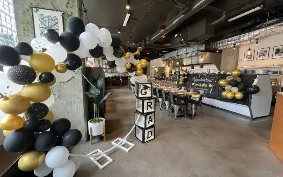 Industrial restaurant decorated for graduation with black, white, and gold.