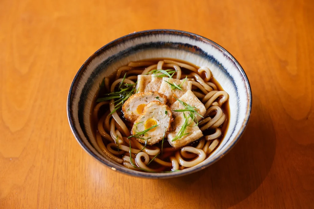 Japanese udon bowl with tofu, halved eggs, and scallions.
