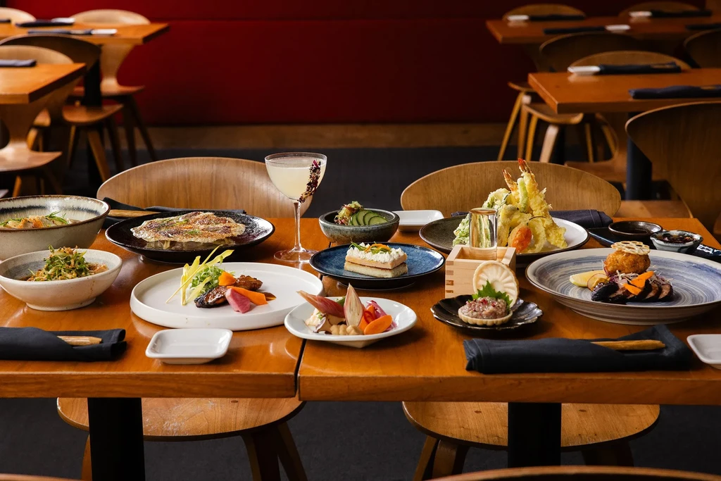 Restaurant table with diverse food plates and a garnished cocktail.