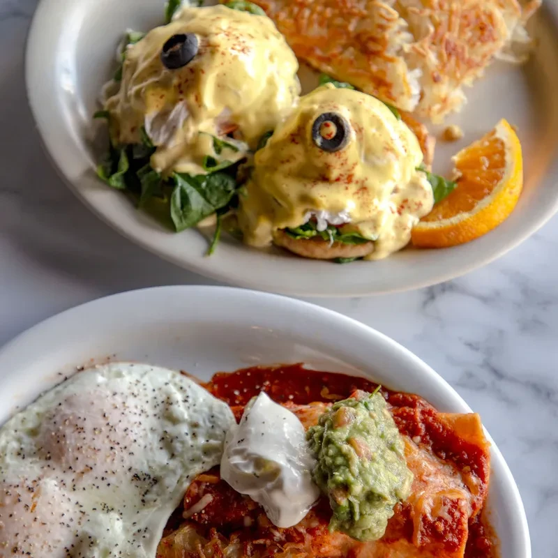 Eggs Benedict and chilaquiles with fried eggs on a marble table.