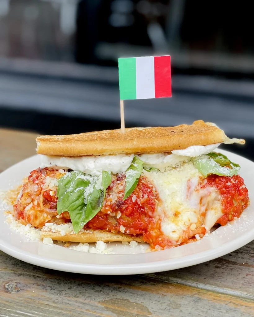 Meatball sub with melted cheese, fresh basil, Italian flag toothpick.