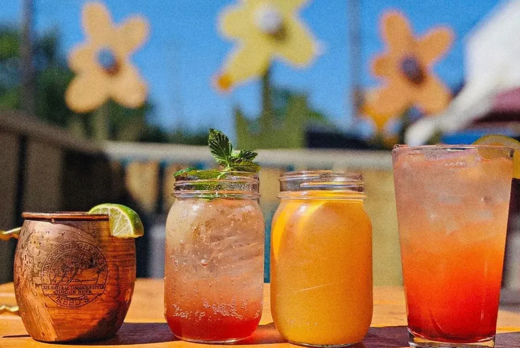 Four vibrant drinks, including Jamaican ginger beer, on an outdoor table.