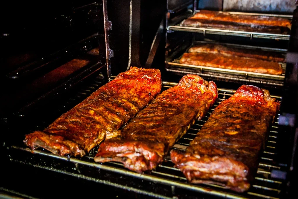 Three glistening racks of ribs cooking inside an oven.
