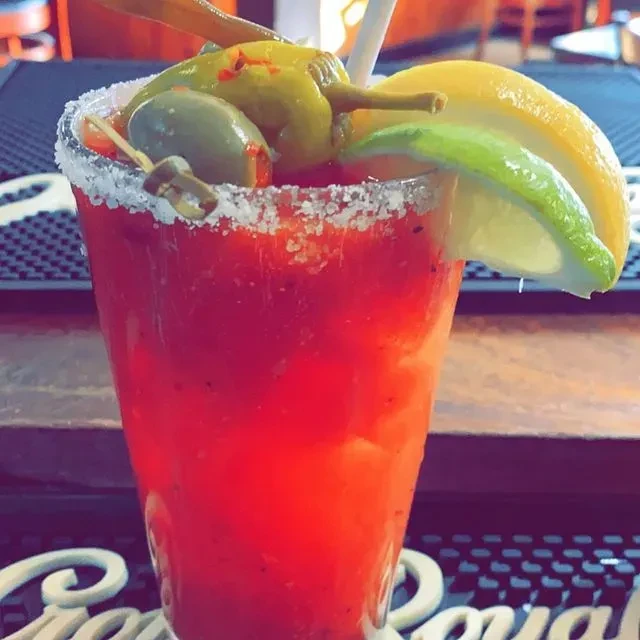 Vibrant red Bloody Mary, salted rim, olives, peperoncini, citrus wedges.
