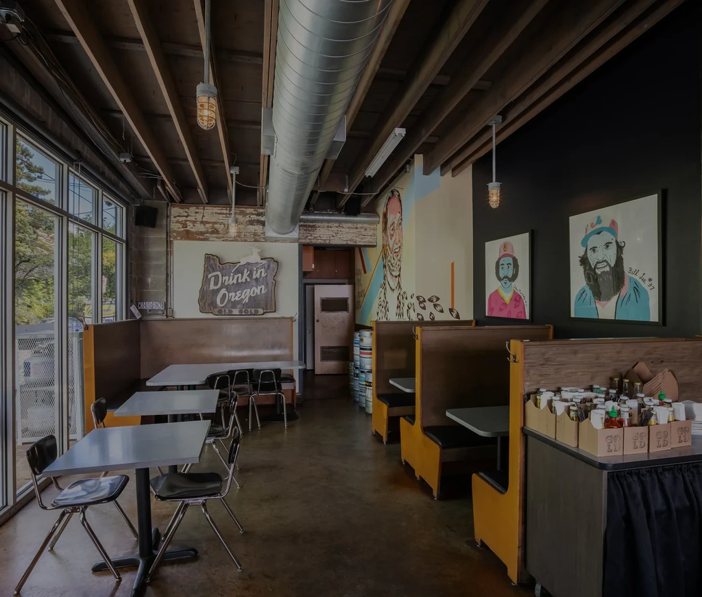 Rustic industrial restaurant interior with booths, mural, and Oregon sign.