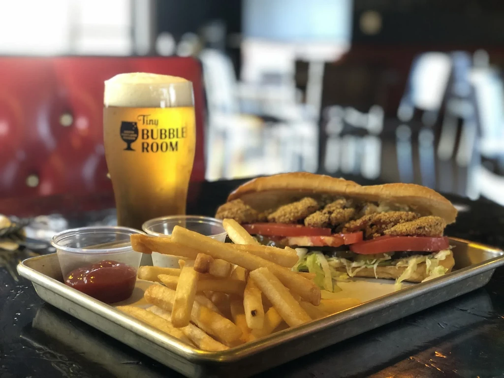 Close-up of fried seafood sub, french fries, and beer in a restaurant.