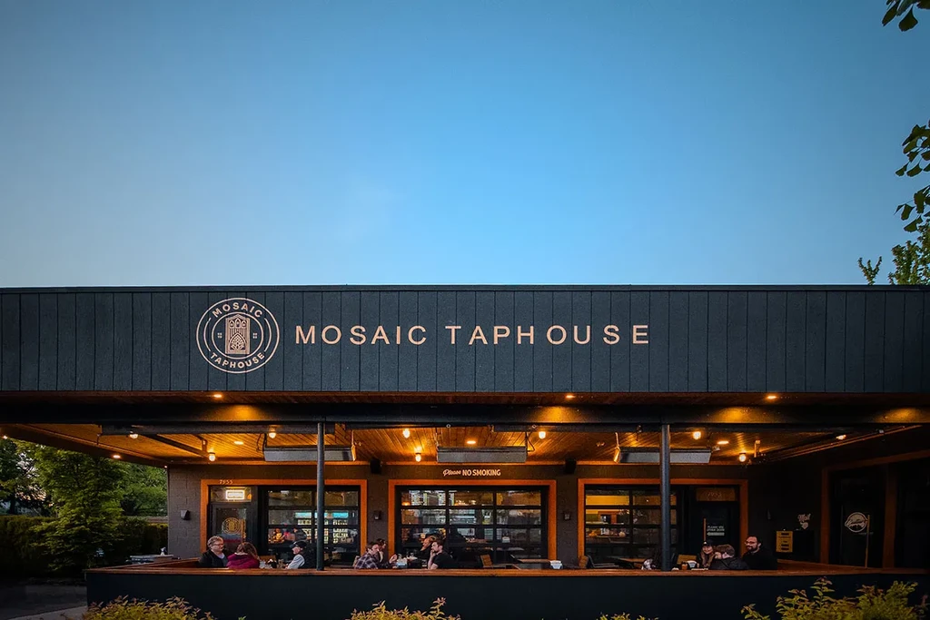 Modern Mosaic Taphouse exterior, showing people on an inviting lighted patio.