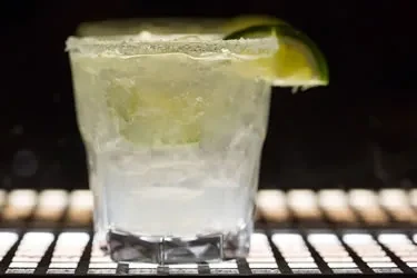 Icy cocktail in textured glass with salted rim and lime.