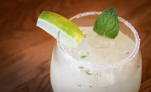 Iced greenish-yellow drink with mint, lime, and a salt/sugar rim.