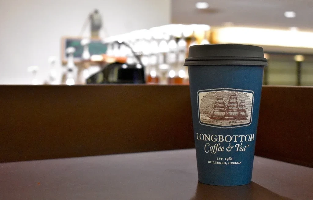 Dark blue Longbottom coffee cup with sailing ship logo on table.
