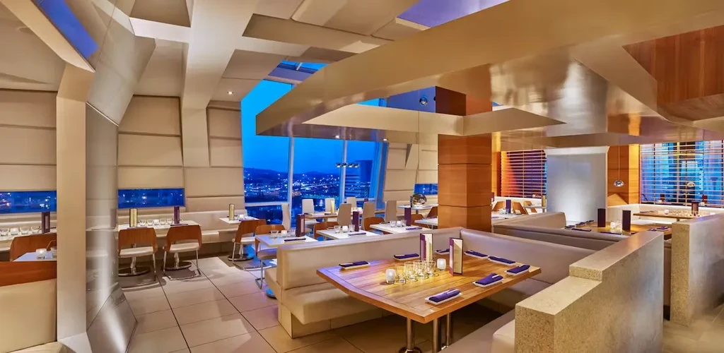 Modern restaurant interior with panoramic city skyline view.
