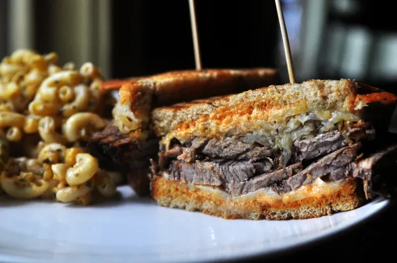 Toasted roast beef sandwich with melted cheese and mac and cheese.