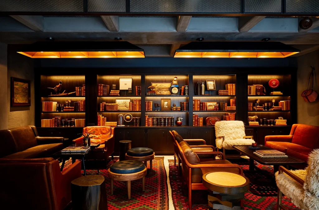 Cozy, sophisticated lounge with a large illuminated bookshelf and seating.