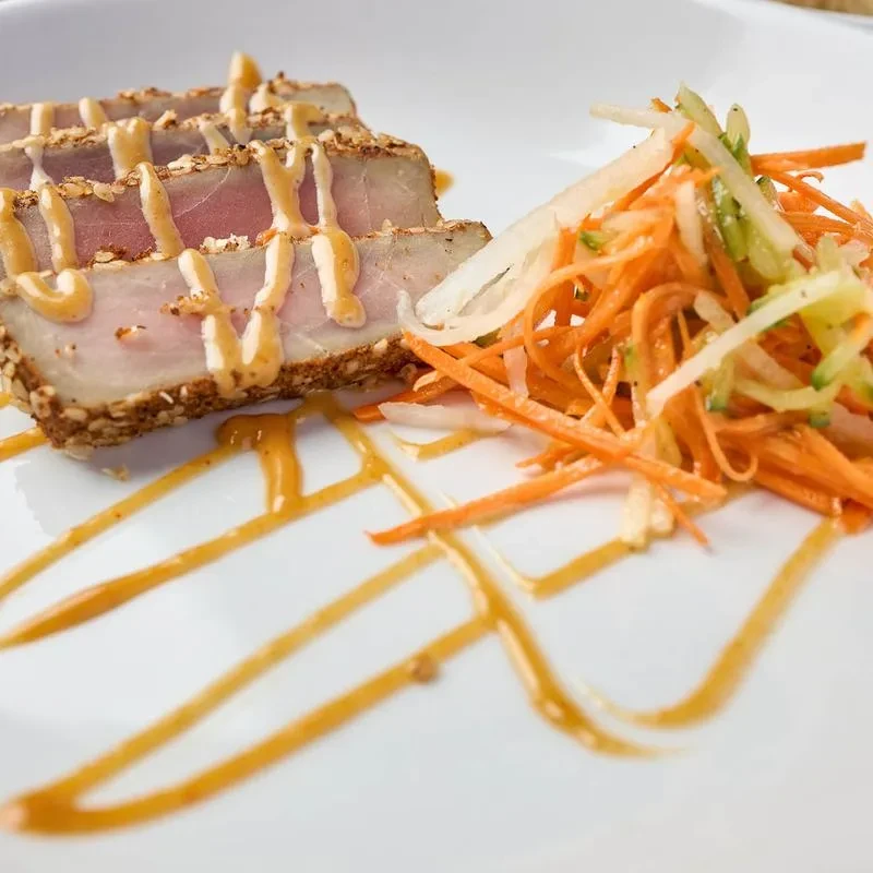 Seared sesame-crusted tuna, carrot slaw, and decorative sauces.