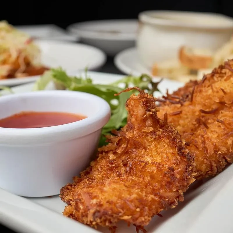 Crispy fried food with red dipping sauce and green lettuce garnish.