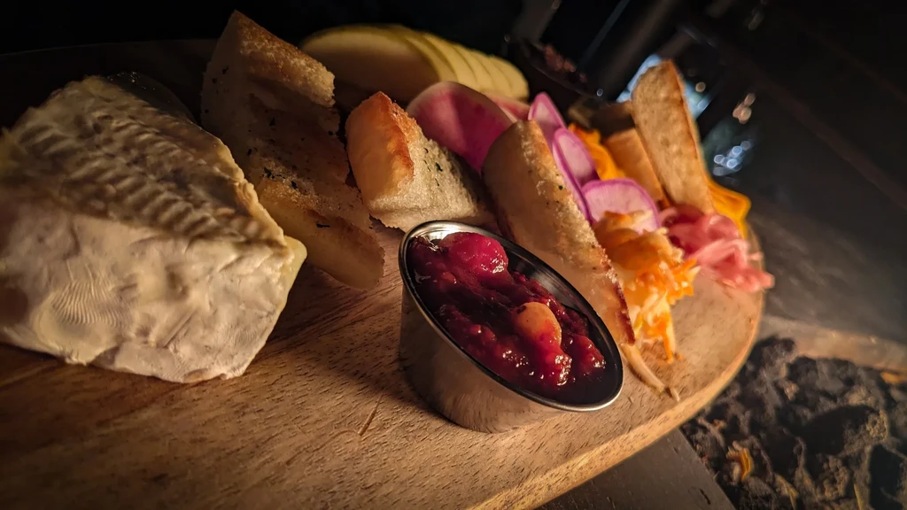 Dimly lit charcuterie board with cheese, bread, compote, and meats.