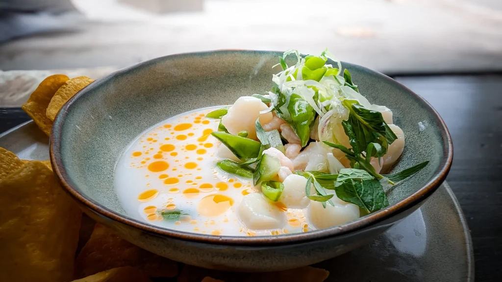 Vibrant creamy ceviche with scallops, shrimp, vegetables, and tortilla chips.