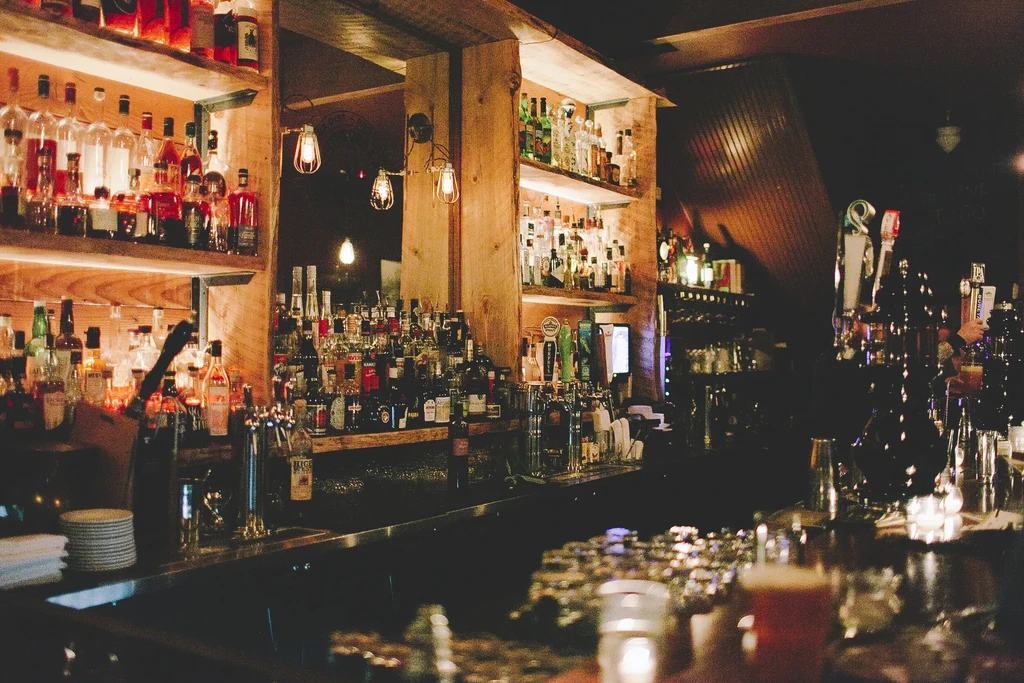 Dimly lit bar interior with liquor bottles, beer taps, and amber drink.