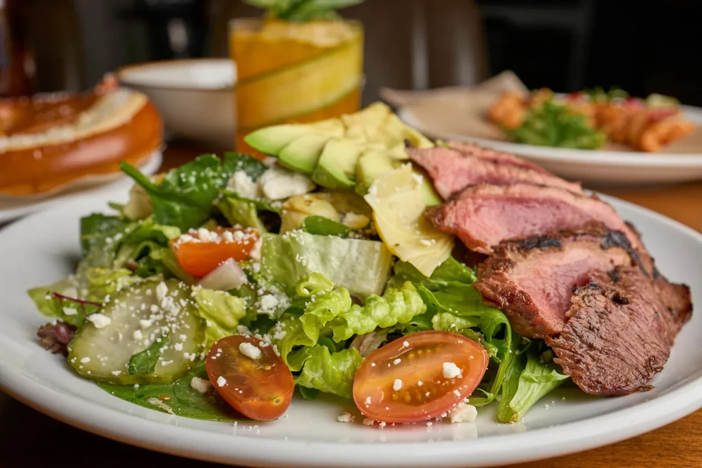 Vibrant steak salad with lettuce, tomatoes, avocado, and feta.