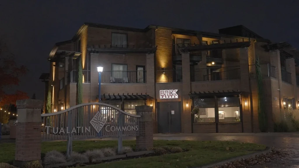 Multi-story brick Brix Tavern building at night with Tualatin Commons sign.