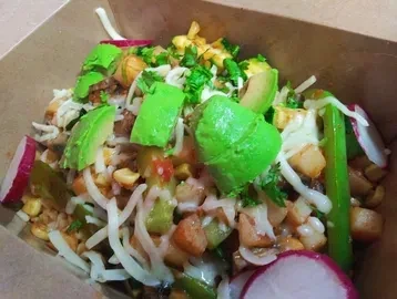 Vibrant food bowl with avocado, corn, and cheese in a takeout container.