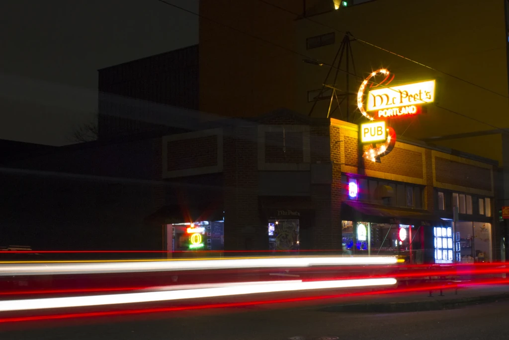 Long-exposure night photo of McPeet's Portland Pub with neon and light trails.
