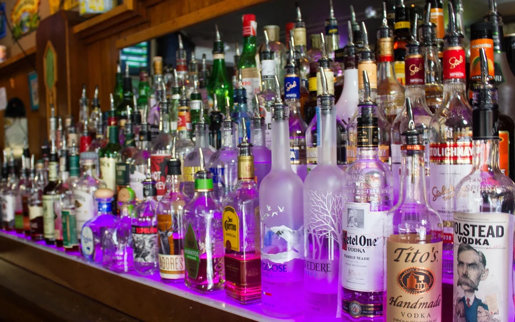 Close-up: Branded liquor bottles on a bar, illuminated by purple LED light.