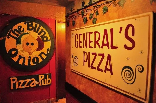 Rustic pizza pub entrance displaying 'Blind Onion' and 'General's Pizza' signs.