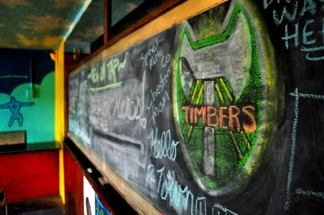 Chalkboard wall with menu text, "TIMBERS" logo, and colorful painted walls.