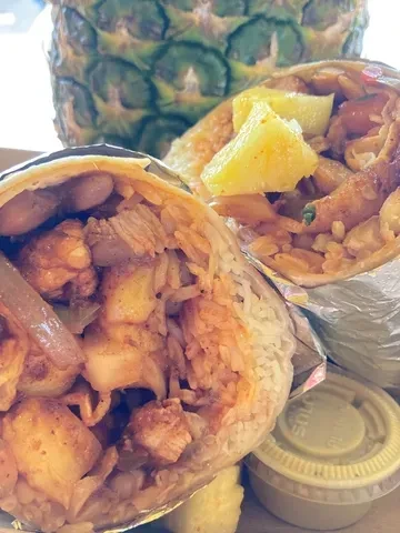 Two burritos, one halved, showing rice, meat, beans, and pineapple.