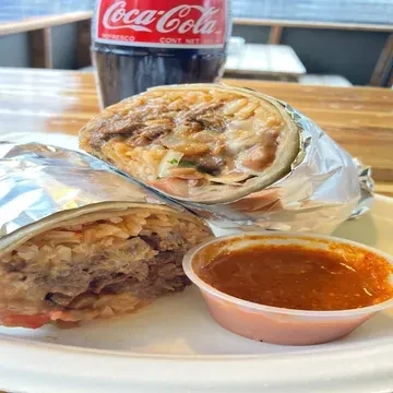 Large burrito cut open, revealing rice, meat, and sauce.