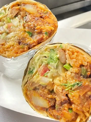Two burritos cut in half, showing colorful fillings and aluminum foil.