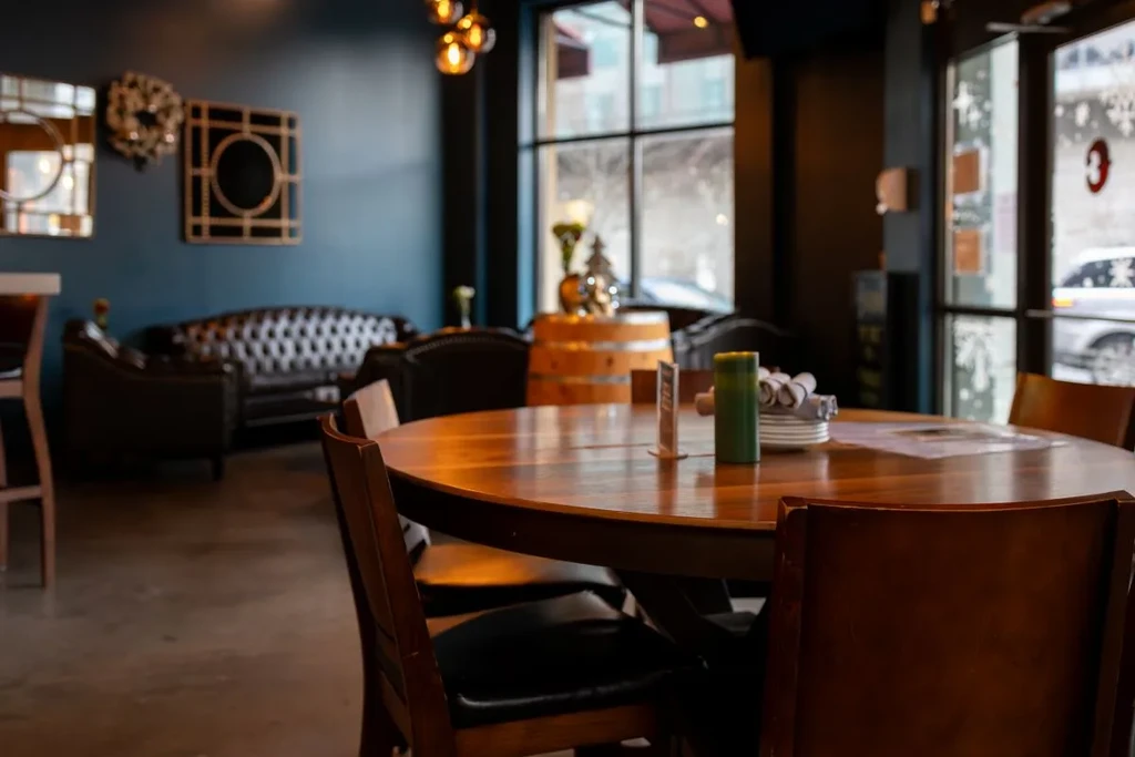 Round wooden table and chairs in a warm restaurant interior.