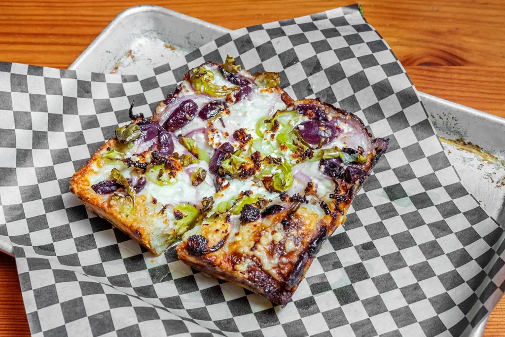 Deep-dish pizza slice with cheese, olives, and green peppers.