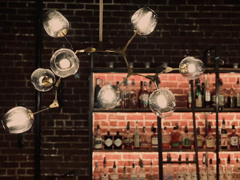 Multi-branched brass chandelier, illuminated glass globes, bar, brick wall.