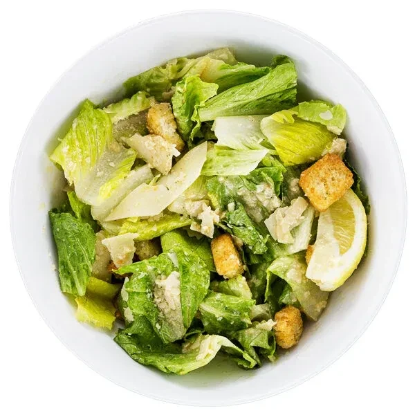 Caesar salad with romaine, croutons, Parmesan, dressing, and lemon wedge.