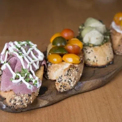 Close-up of various crostini appetizers on a wooden serving board.