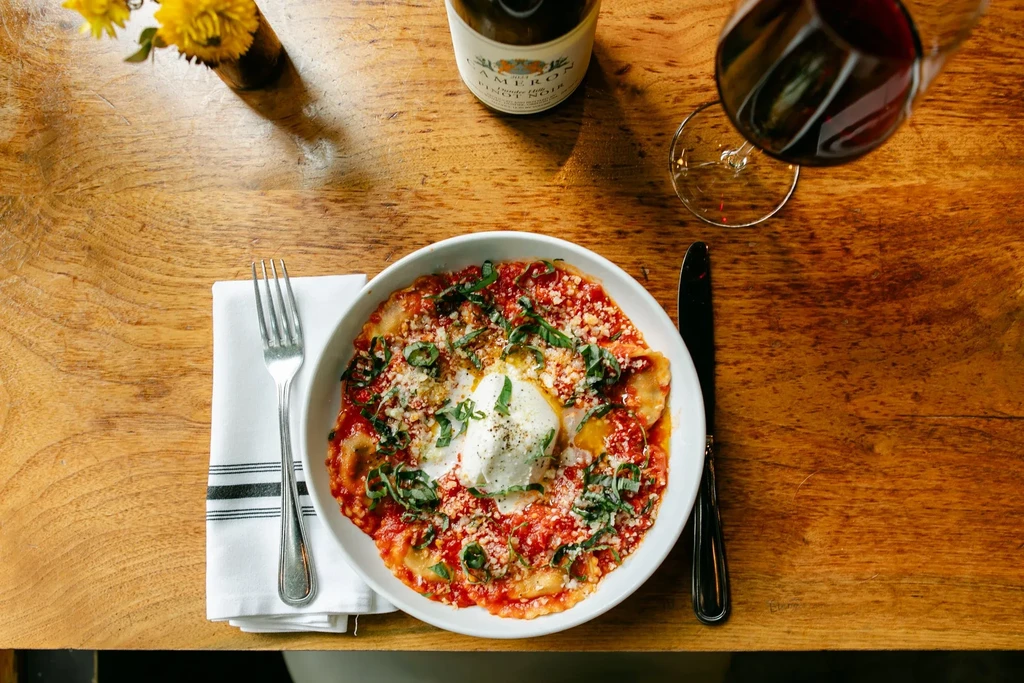 Pasta with red sauce, cheese, basil, wine on rustic wood.