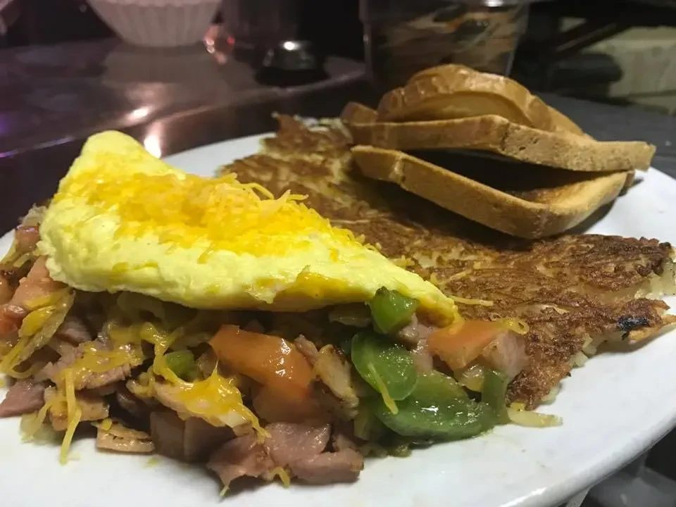 Breakfast plate with a cheesy omelet, hash browns, and stacked toast.