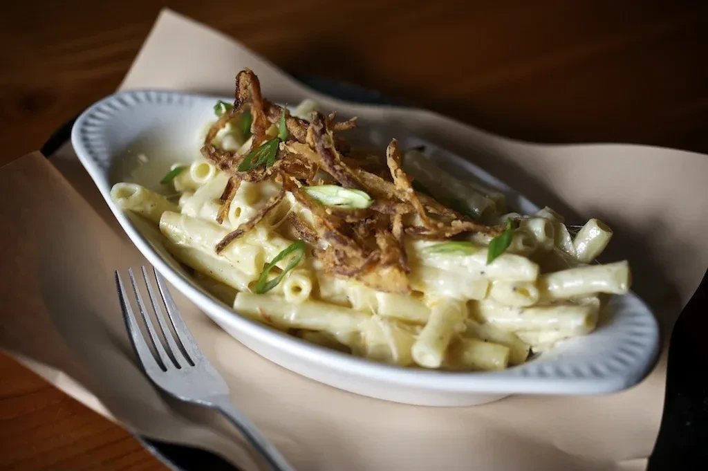 White bowl of macaroni and cheese with crispy fried and green onions.
