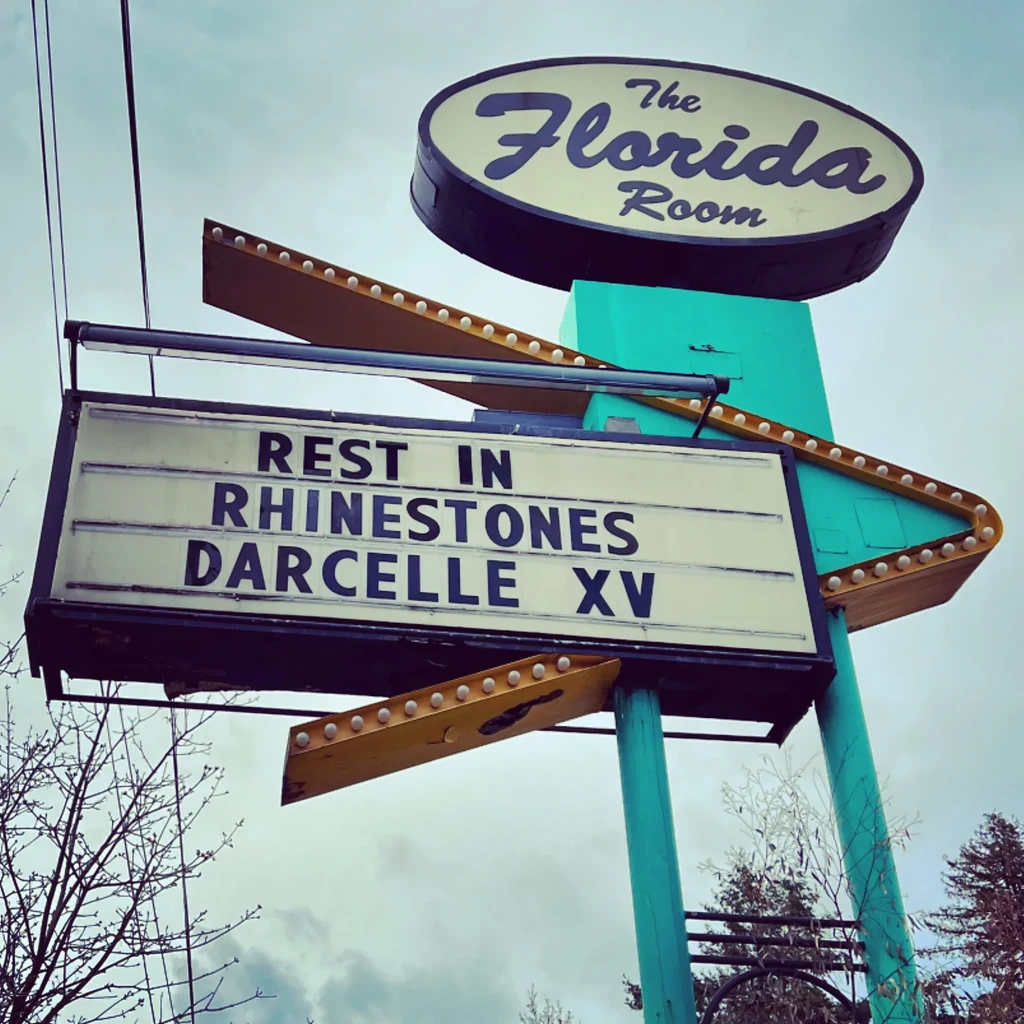 Vintage sign for 'The Florida Room' with 'REST IN RHINESTONES DARCELLE XV'.