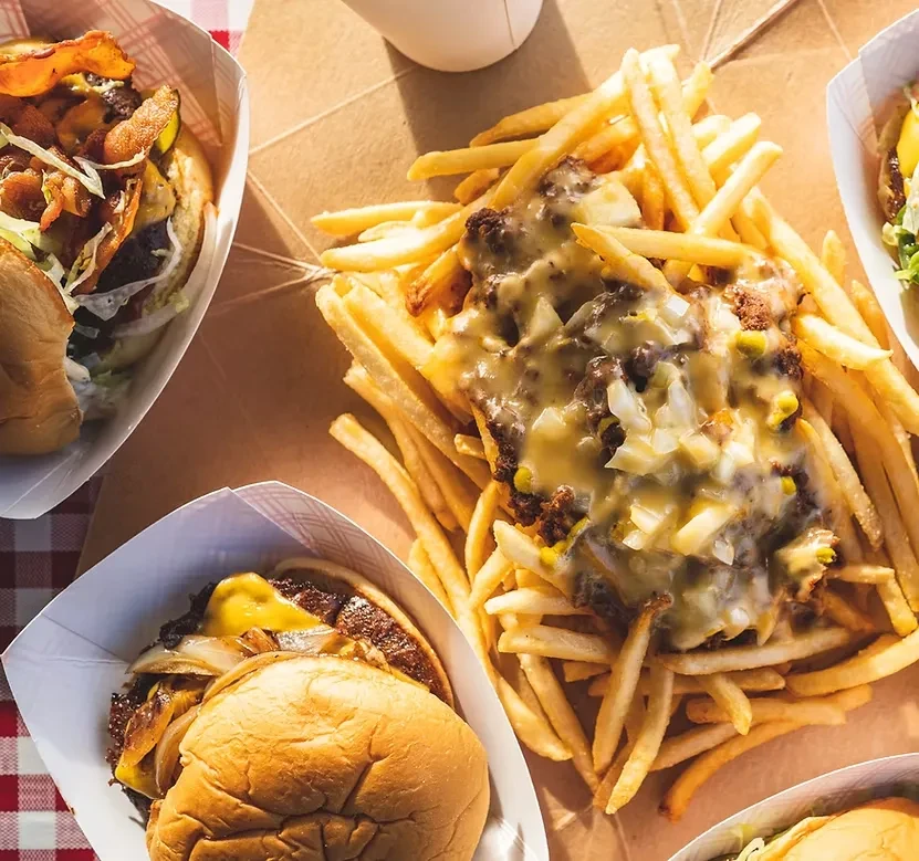 Overhead view of chili cheese fries and several burgers on a casual table.