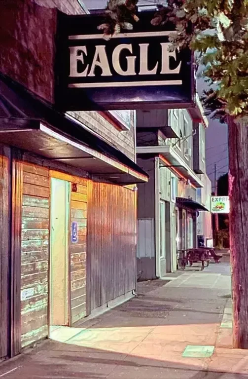 Night street scene: illuminated "EAGLE" sign on a wooden building.