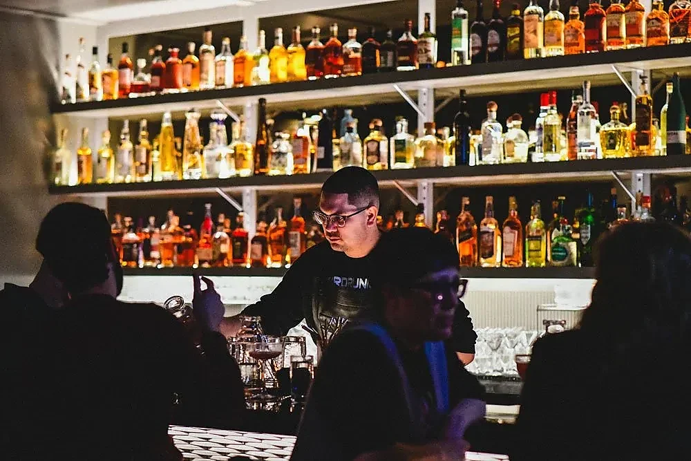 Bartender working in front of fully stocked back bar shelves